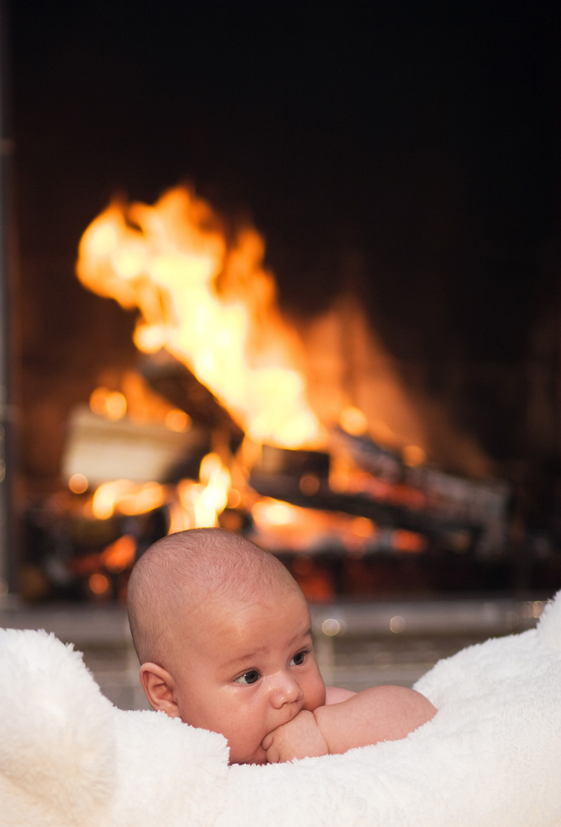 baby is lying on fur on a fireplace background
